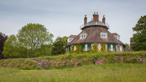 View of the octagonal house at A la Ronde with trees and flowering meadow